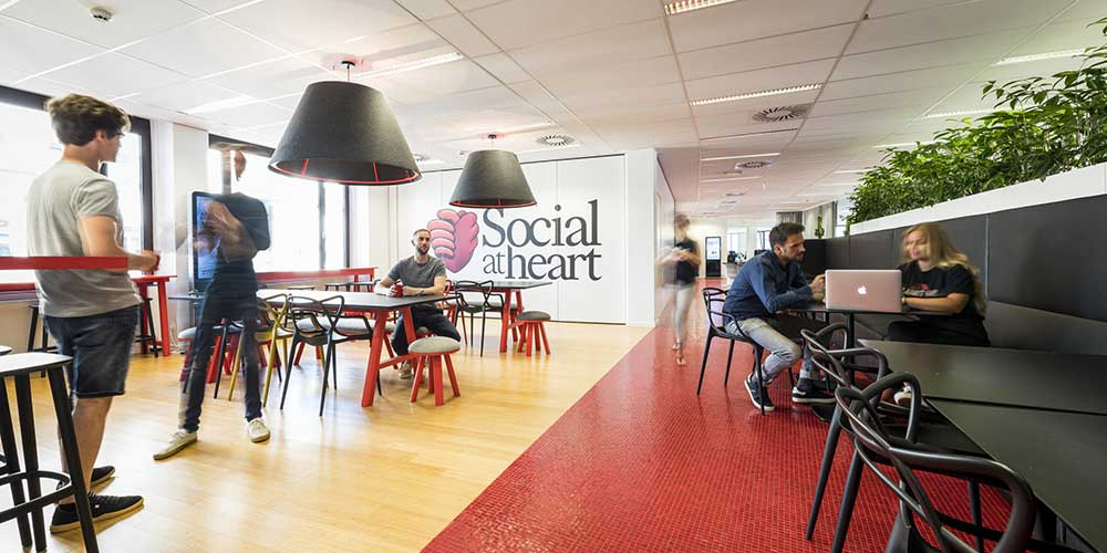 Staff working in an open plan space with 'social at heart' on the wall.